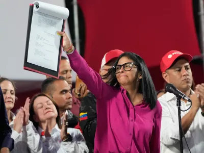 Venezuela's acting President Delcy Rodriguez takes part in a rally holding up a copy of a new law after lawmakers approved legislation opening the nation's oil sector to privatization, at the Miraflores Palace in Caracas, Venezuela, Thursday, Jan. 29, 2026. (AP Photo/Ariana Cubillos)