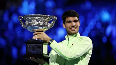 Tennis - Australian Open - Melbourne Park, Melbourne, Australia - February 1, 2026 Spain's Carlos Alcaraz celebrates with the trophy after winning the Australian Open men's singles against Serbia's Novak Djokovic. Alcaraz becomes the youngest man to win all four grand slam titles. REUTERS/Tingshu Wang
