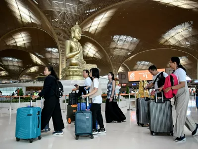 Passengers walk with their luggage past a statue of Buddha on the inauguration day of the newly built Techo International Airport in Kandal province, on the outskirts of Phnom Penh, on September 9, 2025. A new major airport serving the capital Phnom Penh began operations.,Image: 1035477357, License: Rights-managed, Restrictions:, Model Release: no