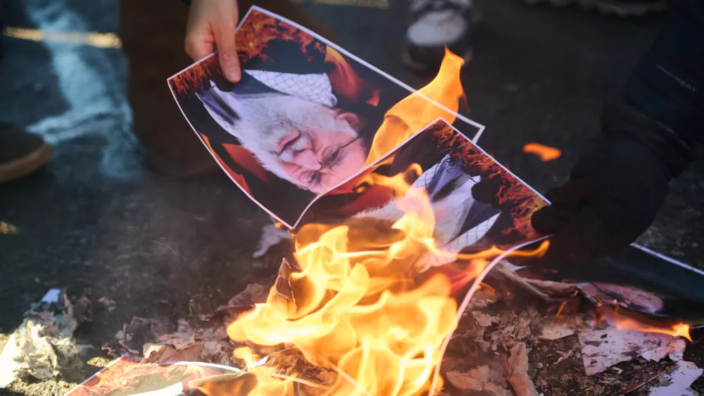 Protesters burn pictures of Iranian Supreme Leader Ayatollah Ali as they march in support of regime change in Iran during a protest in Toronto, on Sunday, Feb. 1, 2026. (Sammy Kogan/The Canadian Press via AP)