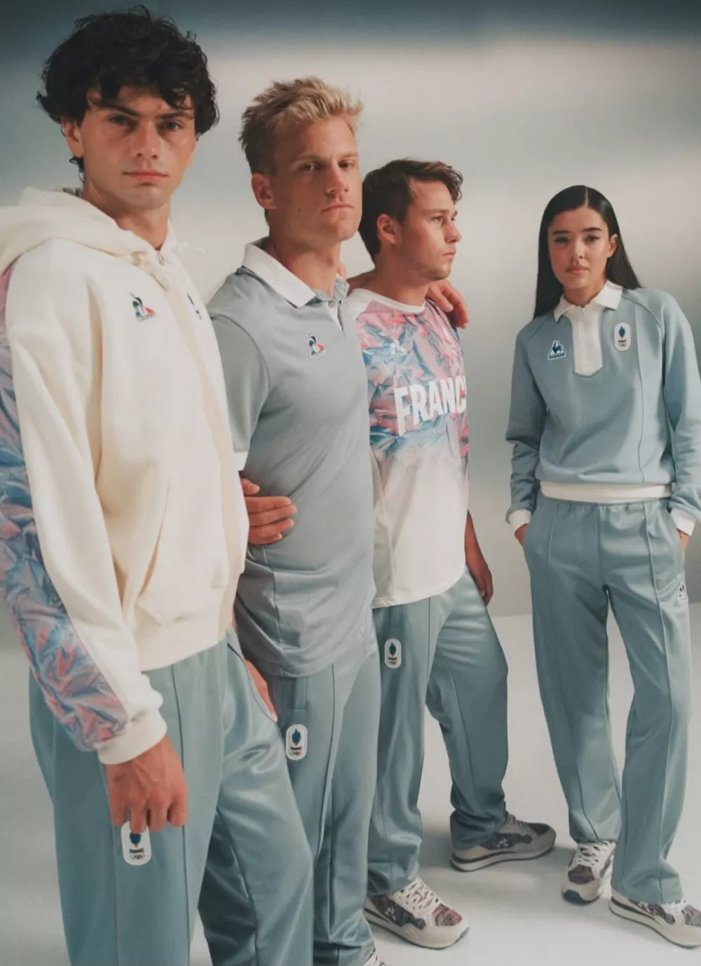 Uradna kolekcija Le Coq Sportif za leto 2026 za francosko ekipo združuje nacionalno tribarvno paleto modre, bele in rdeče v umirjeno paleto ledeno modre, krem ​​in nežno rdeče z zimskimi kosi, pripravljenimi za ekstremne razmere. F IG