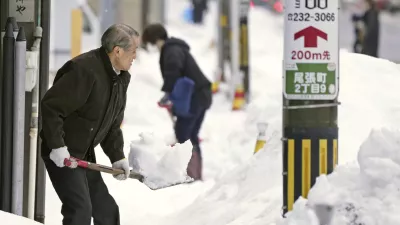 Residents shovel snow off a sidewalk in Kanazawa, Ishikawa prefecture, central Japan, on Dec. 24, 2022. (Kyodo News via AP)