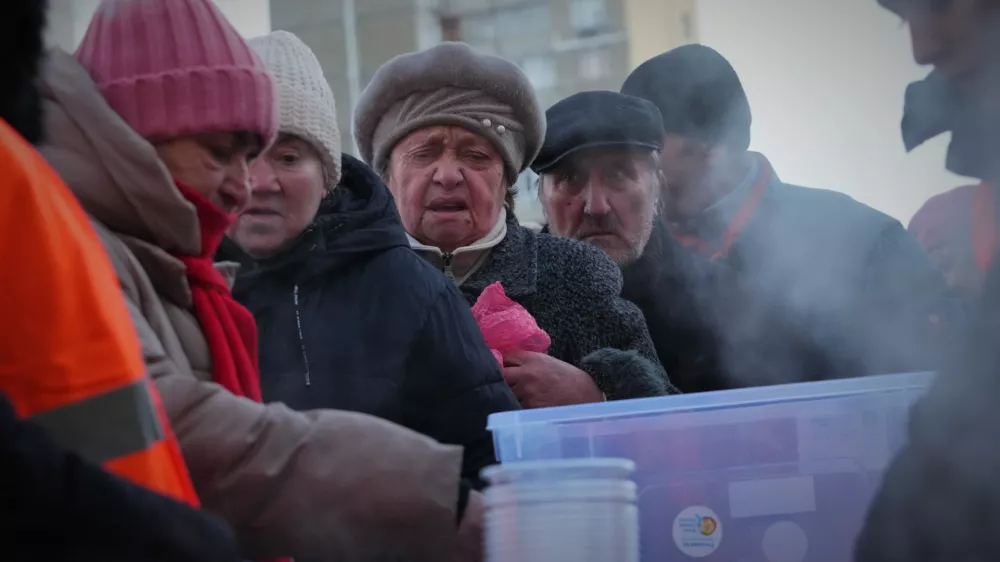 People line up to get a free hot food during a blackout caused by Russia's regular air attacks on the country's energy system in Kyiv, Ukraine, Monday, Feb. 2, 2026. (AP Photo/Sergei Grits)