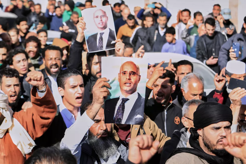 Libyans march to attend the funeral of Seif al-Islam, son of former Libyan Leader Moammar Gadhafi, as they hold a poster of his father in Bani Walid city, Libya, Friday, Feb. 6, 2026. (AP Photo/Yousef Murad)