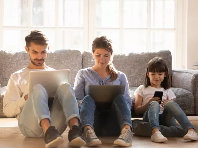 Family with kid sitting on floor at home using laptops and phone, parents and little child daughter consumers customers obsessed with devices gadgets, people internet technology addiction concept