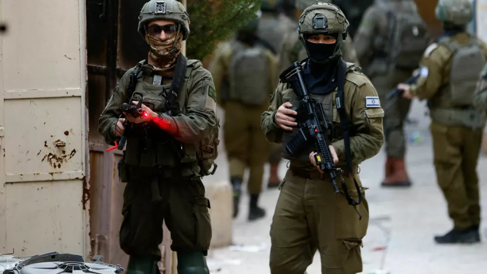 Israeli soldier points his weapon towards the camera, during a weekly settlers' tour in Hebron, in the Israeli-occupied West Bank, February 7, 2026. REUTERS/Mussa Qawasma