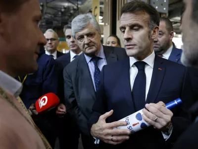 French President Emmanuel Macron holds a bottle of wine next to French junior Minister in charge of external trade Nicolas Forissier as he visits the Wine Paris 2026 fair, at the Porte de Versailles exhibition center in Paris, France, 09 February 2026. YOAN VALAT/Pool via REUTERS
