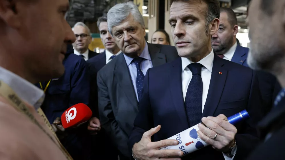 French President Emmanuel Macron holds a bottle of wine next to French junior Minister in charge of external trade Nicolas Forissier as he visits the Wine Paris 2026 fair, at the Porte de Versailles exhibition center in Paris, France, 09 February 2026. YOAN VALAT/Pool via REUTERS