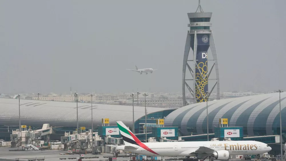 FILE - An Emirates Boeing 777 stands at the gate at Dubai International Airport as another prepares to land on the runway in Dubai, United Arab Emirates, Aug. 17, 2022. (AP Photo/Jon Gambrell, File)