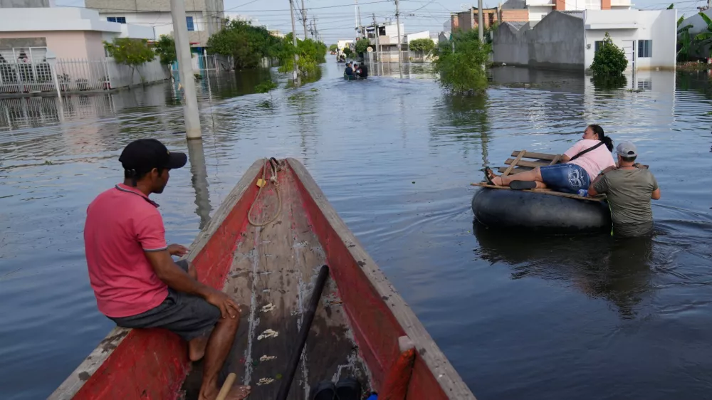 Residents wade through a flooded neighborhood in Monteria, Colombia, Tuesday, Feb. 10, 2026. (AP Photo/Fernando Vergara)