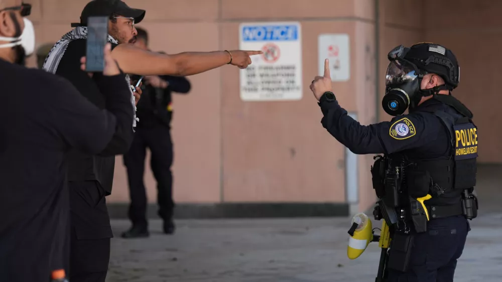Protestors protests with U.S. Immigration and Customs Enforcement (ICE) agents outside the Los Angeles Metropolitan Detention Center (MDC Los Angeles) as part of the nationwide Spring Surge to Melt ICE! on Friday, Feb. 13, 2026. (AP Photo/Damian Dovarganes)