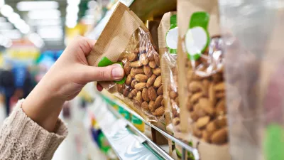 Hand of the buyer with the packaging of almond nuts in the store