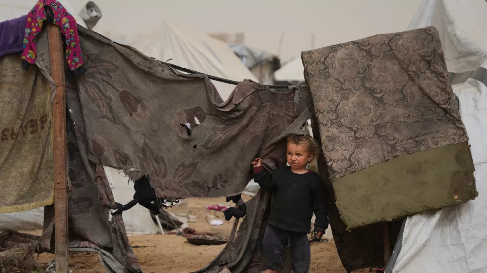 Palestinian child looks on as he stands next to a tent at a makeshift camp for displaced people during a dust storm in Zawaida, in the central Gaza Strip, Saturday, Feb. 14, 2026. (AP Photo/Abdel Kareem Hana)