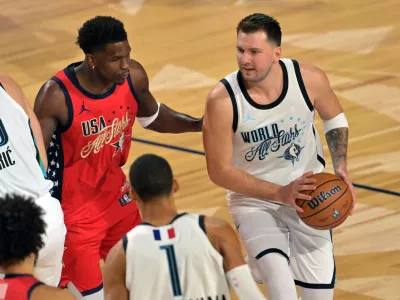 Feb 15, 2026; Inglewood, California, USA; Team World guard Luka Doncic (77) of the Los Angeles Lakers controls the ball against Team USA Stars guard Anthony Edwards (5) of the Minnesota Timberwolves in game one during the 75th NBA All Star Game at Intuit Dome. Mandatory Credit: Jayne Kamin-Oncea-Imagn Images