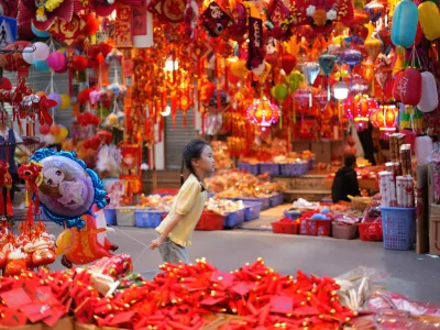 A young girl runs with a balloon at Hang Luoc traditional Tet market ahead of the Lunar New Year of the Horse in Hanoi, Vietnam, Sunday, Feb 15, 2026. (AP Photo/Hau Dinh)