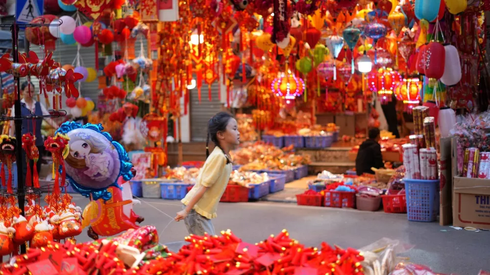 A young girl runs with a balloon at Hang Luoc traditional Tet market ahead of the Lunar New Year of the Horse in Hanoi, Vietnam, Sunday, Feb 15, 2026. (AP Photo/Hau Dinh)