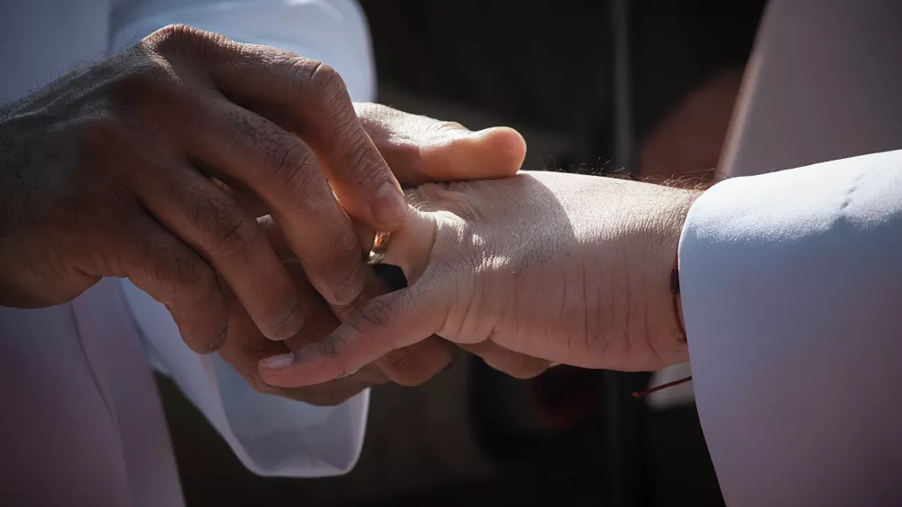 A person places a wedding ring on their partner's finger as they marry during the "Love in Times Square" event on Valentine's Day, Saturday, Feb. 14, 2026, in New York. (AP Photo/Andres Kudacki)