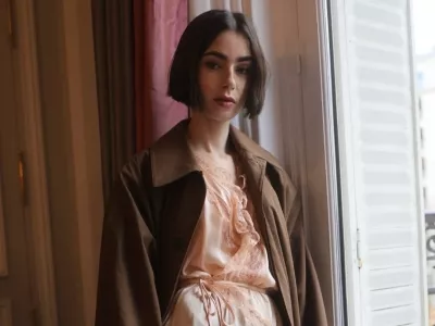 Minulo nedeljo je Lily Collins, ki v seriji Netflix Emily v Parizu igra glavno junakinjo, prispela v Pariz z vlakom Venice Simplon-Orient-Express in bila ujeta v objektivih med promocijo prihajajoče sezone. Nosila je drzen, blush toniran kos spodnjega perila, ki ga je Saint Laurent oblikoval Anthony Vaccarello, oblečenega skupaj s čokoladno rjavim trench pla&scaron;čem in usnjenim clutch torbico. Outfit velja za enega najbolj drznih, ki jih je Collins nosila doslej, &scaron;e posebej za igralko, katere osebni slog se običajno nagiba k klasični eleganci. Nova sezona Emily v Parizu bo na Netflixu na voljo 22. decembra 2025, kar bo priložnost, da gledalci ponovno vidijo Emily v drzni modni izbiri.