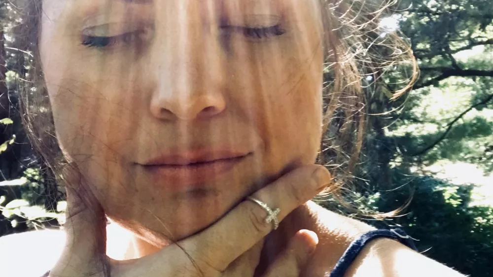 Beautiful middle aged woman, a portrait shot of face only, model is outside in the sun, with very distinct rays of sunlight making dramatic ray marks on her face. Her eyes are closed in relaxation and happiness, feeling the warmth. Model has dark brown, upswept hair and an off the shoulder top. / Foto: Jamie Casper