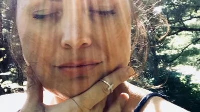 Beautiful middle aged woman, a portrait shot of face only, model is outside in the sun, with very distinct rays of sunlight making dramatic ray marks on her face. Her eyes are closed in relaxation and happiness, feeling the warmth. Model has dark brown, upswept hair and an off the shoulder top. / Foto: Jamie Casper