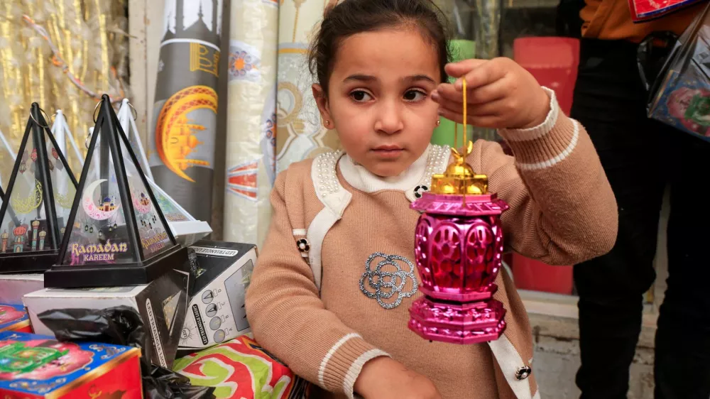 A Palestinian girl holds a Ramadan lantern at a market where seasonal decorations are sold, in Khan Younis in the southern Gaza Strip, February 14, 2026. REUTERS/Haseeb Alwazeer