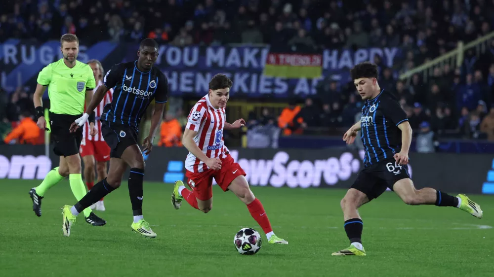Atletico Madrid's Julian Alvarez, centre, and Brugge's Kyriani Sabbe, right, challenge for the ball during the Champions League play-off first leg soccer match between Club Brugge and Atletico Madrid, in Bruges, Belgium, Wednesday, Feb. 18, 2026. (AP Photo/Omar Havana)