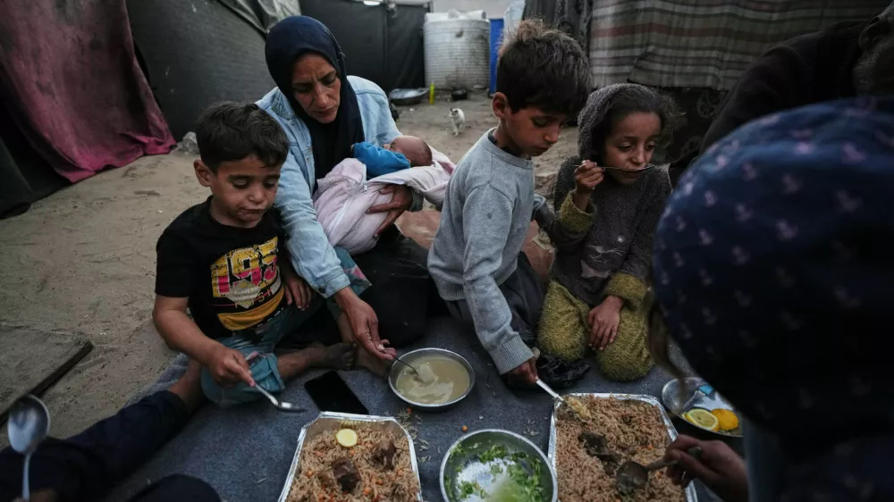 Displaced members of the Al-Zamli family break their fast on the first day of Ramadan inside their tent in Khan Younis, Gaza Strip, Wednesday, Feb. 18, 2026. (AP Photo/Jehad Alshrafi)