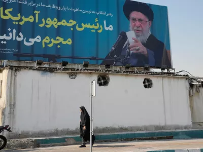 A woman walks past a billboard with an image of Iranian Supreme Leader Ayatollah Ali Khamenei with a quotation of him which says: "We recognise the President of America as a criminal," in Tehran, Iran, Tuesday, Feb. 17, 2026. (AP Photo/Vahid Salemi)