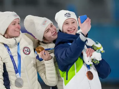Gold medalist Anna Odine Stroem, of Norway, celebrates on the podium flanked by silver medalist Eirin Maria Kvandal, also of Norway, and bronze medalist Nika Prevc, of Slovenia, right, after the ski jumping women's large hill individual at the 2026 Winter Olympics, in Predazzo, Italy, Sunday, Feb. 15, 2026. (AP Photo/Evgeniy Maloletka)