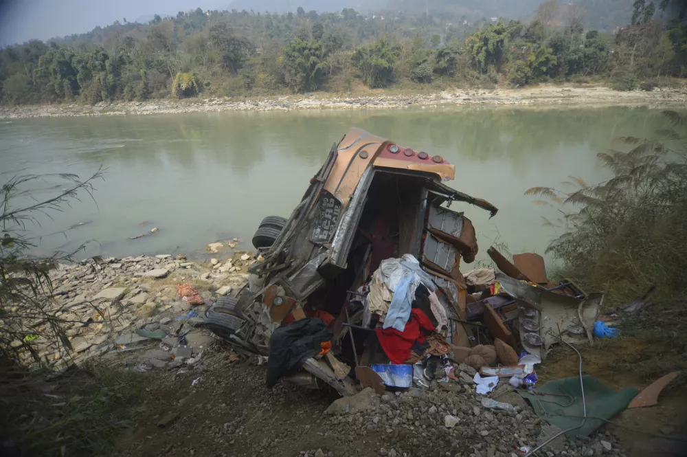 The wreckage of a bus is seen on the bank of the Trishuli River after it drove off a mountain highway near Benighat, west of the capital, Kathmandu, Nepal, Monday, Feb. 23, 2026. (AP Photo/Bijay Rai)
