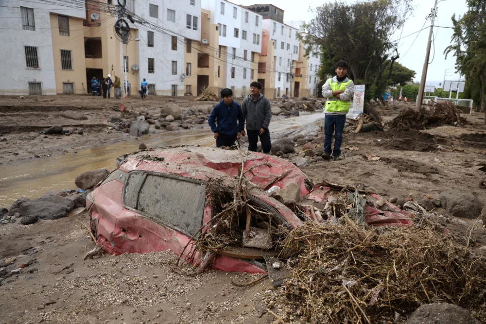 People inspect the road destroyed by heavy rain that triggered flooding in Arequipa, Peru, Monday, Feb. 23, 2026. (AP Photo/Jose Sotomayor)