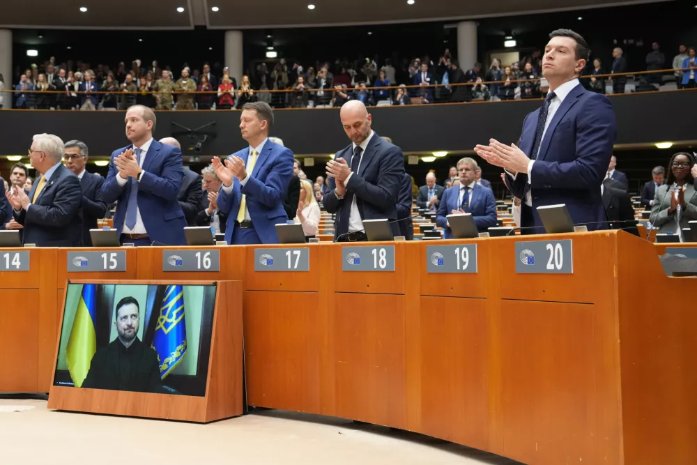 Member of European Parliament Jordan Bardella, right, applauds after an address by Ukraine's President Volodymyr Zelenskyy via video link, during an extraordinary plenary session held for the fourth anniversary of Russia's invasion of Ukraine, at the European Parliament in Brussels, Tuesday, Feb. 24, 2026. (AP Photo/Marius Burgelman)