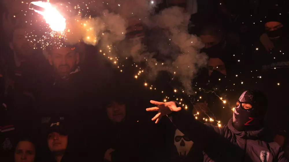A Partizan soccer fan hits torch during a Serbian National soccer league derby match between Red Star and Partizan in Belgrade, Serbia, Sunday, Feb. 22, 2026. (AP Photo/Darko Vojinovic)
