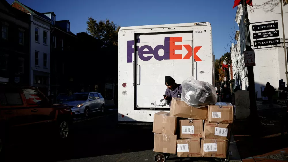 FILE PHOTO: A driver of FedEx stands with packages near a delivery truck during Black Friday preparations in the Georgetown neighborhood of Washington, U.S., November 26, 2024. REUTERS/Benoit Tessier/File Photo