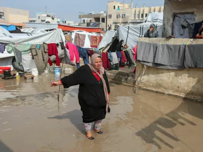 A woman stands amid water following heavy rains, near shelters of Palestinians displaced during the two-year Israeli offensive, in Khan Younis in the southern Gaza Strip, February 24, 2026. REUTERS/Ramadan Abed