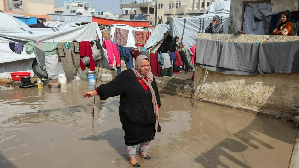 A woman stands amid water following heavy rains, near shelters of Palestinians displaced during the two-year Israeli offensive, in Khan Younis in the southern Gaza Strip, February 24, 2026. REUTERS/Ramadan Abed