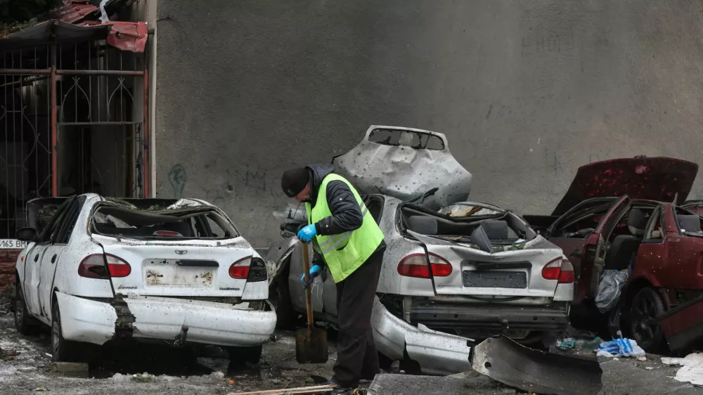 A municipal worker removes debris next to damaged cars outside an apartment building hit by a Russian drone strike on Thursday, amid Russia's attack on Ukraine, in Kharkiv, Ukraine February 26, 2026. REUTERS/Vyacheslav Madiyevskyy