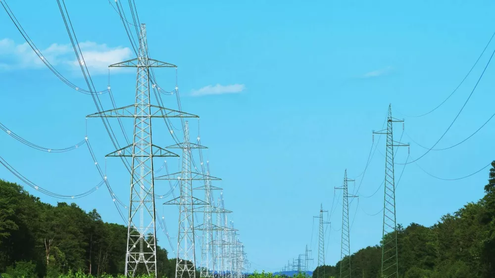 Long line of transmission towers on deforestated strip going through forest area. Electricity, power transmission and distribution, electrical energy, clean energy and environment concepts / Foto: Robertax