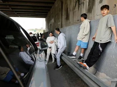 People take shelter under the bridge of a highway after Israel's military announced they identified missiles launched from Iran towards Israel and sirens are sounded, near Latrun, Israel, February 28, 2026. REUTERS/Amir Cohen