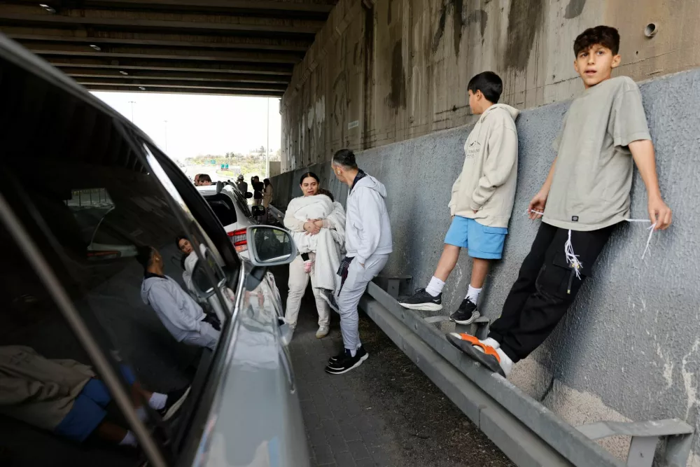 People take shelter under the bridge of a highway after Israel's military announced they identified missiles launched from Iran towards Israel and sirens are sounded, near Latrun, Israel, February 28, 2026. REUTERS/Amir Cohen