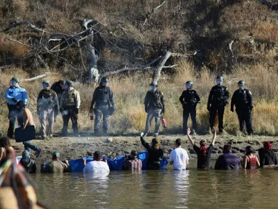 FILE - In this Nov. 2, 2016 file photo, protesters demonstrating against the expansion of the Dakota Access Pipeline wade in cold creek waters confronting local police as remnants of pepper spray waft over the crowd near Cannon Ball, N.D. (AP Photo/John L. Mone, File)