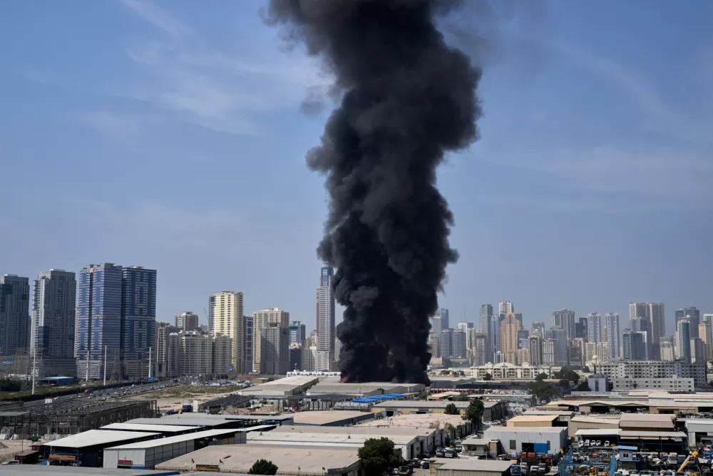 A black plume of smoke rises from a warehouse at the industrial area of Sharjah City in the United Arab Emirates following reports of Iranian strikes in Dubai, United Arab Emirates, Sunday, March 1, 2026. (AP Photo/Altaf Qadri)