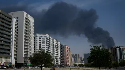 A cyclist rides past as black plume of smoke is seen rising from a warehouse at the industrial area of Sharjah City in the United Arab Emirates following reports of Iranian strikes in Dubai, United Arab Emirates, Sunday, March 1, 2026. (AP Photo/Altaf Qadri)