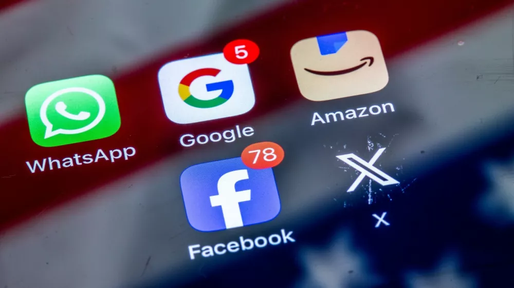 ILLUSTRATION - 10 April 2025, Mecklenburg-Western Pomerania, Schwerin: The apps of various American tech companies, WhatsApp, Google, Amazon, Facebook and X can be seen on the display of a smartphone on which the American flag is reflected. Photo: Jens B&uuml;ttner/dpa,Image: 985843779, License: Rights-managed, Restrictions: GERMANY OUT, Model Release: no