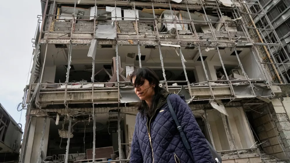 A woman walks by the damaged Gandhi Hospital, which was hit when a strike struck a state TV communications tower and nearby buildings across the street during the ongoing joint U.S.-Israeli military campaign in Tehran, Iran, Monday, March 2, 2026. (AP Photo/Vahid Salemi)