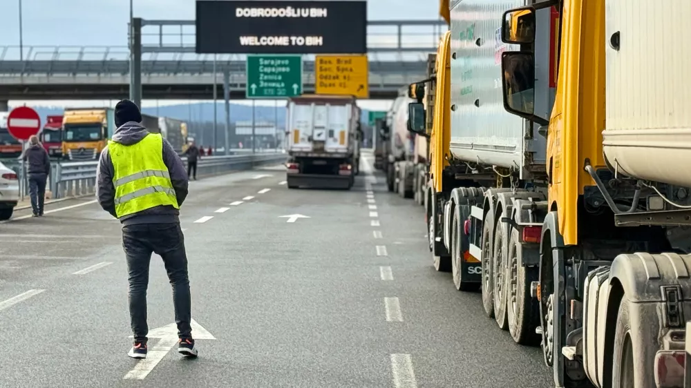 A man stands next to a line of trucks and buses on the Bosnian side of the border with Croatia, in Svilaj, Bosnia, Monday, Jan. 26, 2026, as drivers across the Balkans blocked dozens of border crossings in the region in protest over newly introduced European Union entry regulations.(AP Photo/Eldar Emric)