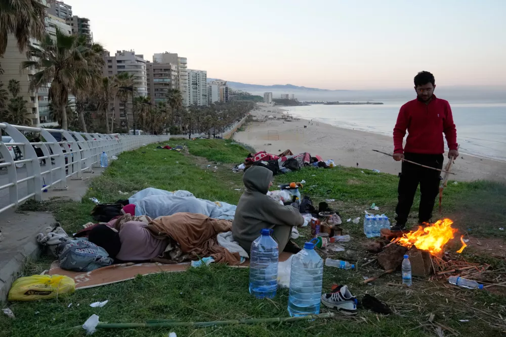 A displaced man with his family fleeing Israeli airstrikes in Beirut's southern suburb of Dahiyeh sets fire to warm themselves on the Beirut corniche, Lebanon, Friday, March 6, 2026. (AP Photo/Hussein Malla)