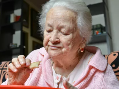 Old woman eating a slice of bread at home