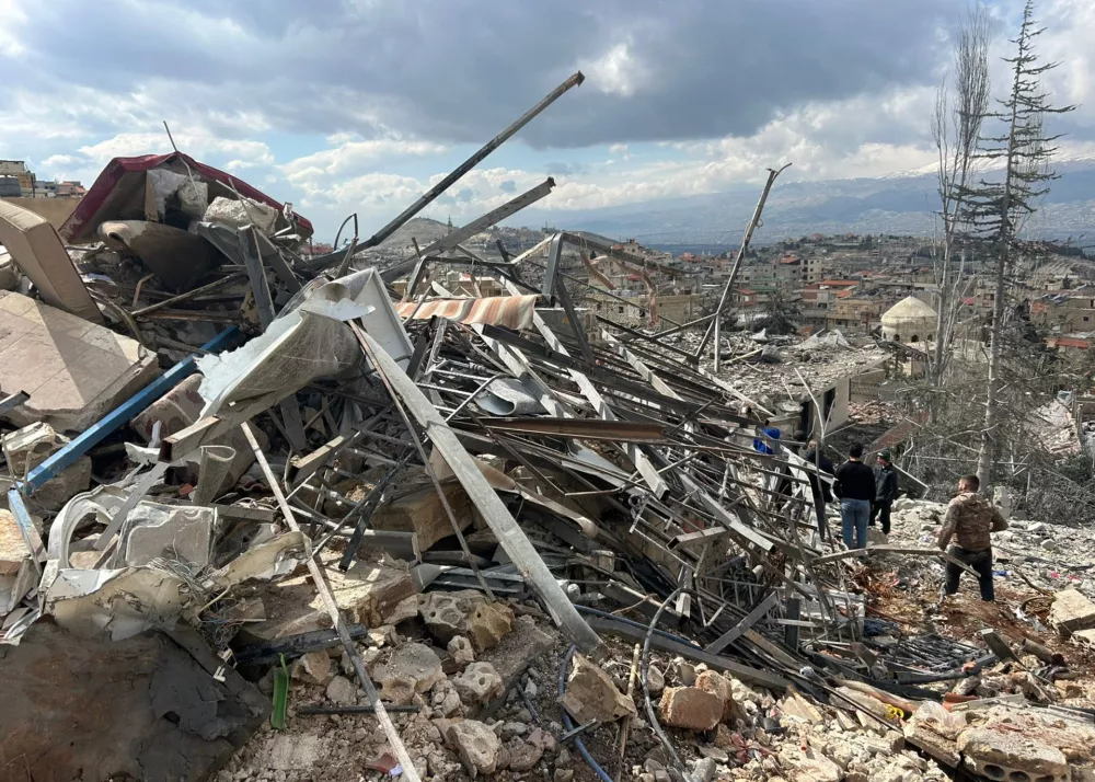 People check the damage left by Israeli airstrikes late Friday, in the village of Nabi Chit, eastern Lebanon, Saturday, March 7, 2026, where Israeli forces landed overnight and dug a grave in a cemetery searching for Israeli co-pilot Ron Arad who was captured and then went missing after his fighter jet crashed over south Lebanon in 1986. (AP Photo/Ali Salem)