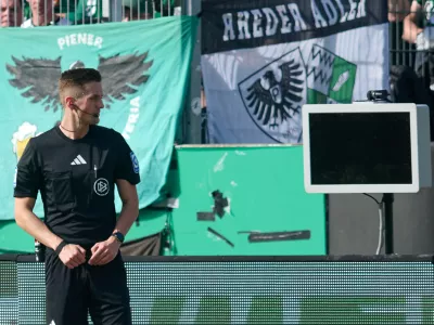 Referee Felix Bickel stands in front of the dark screen as he tries to review a VAR decision on a penalty kick for Berlin during the Bundesliga 2 soccer game between Muenster and Hertha Berlin in Muenster, Germany, Sunday March 8, 2026. (Bernd Thissen/dpa via AP)